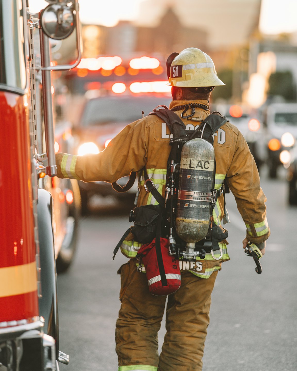 Firefighter in bunker gear stands by a red fire truck.